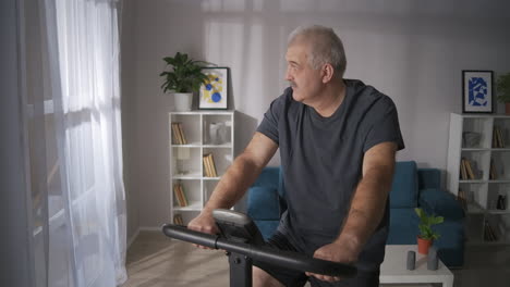 calm-middle-aged-man-is-spinning-pedals-of-exercise-bike-in-home-sport-activities-with-equipment-cardio-training-for-adult-people